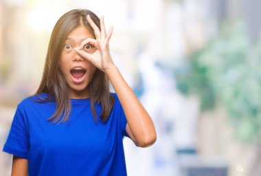 Sürpriz yüz, göz parmaklarının arasından seyir ile ok jest yapıyor izole arka plan üzerinde Genç Asyalı kadın şok. İmansız ifade.