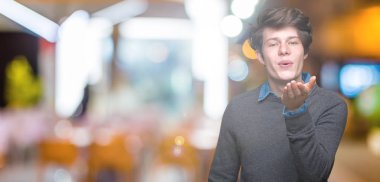 Genç yakışıklı zarif adam izole arka plan bir öpücük el ile güzel ve seksi olmak hava üfleme kamera bakıyor. Aşk ifade.