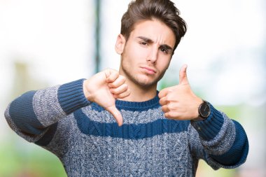 Yakışıklı delikanlı izole arka plan yapmaya başparmak yukarı ve aşağı, anlaşmazlık ve anlaşma ifade üzerinde. Deli çatışma