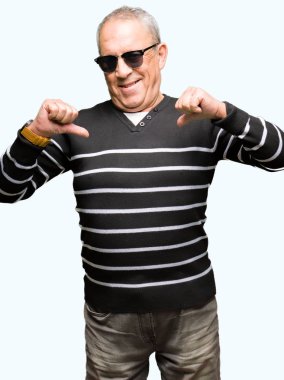 Kış kazak ve yüzünde gülümseme ile kendinden emin görünüyorsun, kendini gururlu ve mutlu parmakları ile işaret güneş gözlüğü takan yakışıklı komuta sizde.