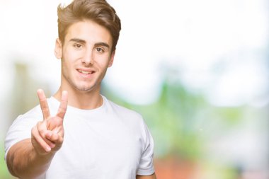 Yakışıklı delikanlı gösterilen ve parmakları ile işaret izole arka plan üzerinde beyaz t-shirt giyen ikincisi ise kendinden emin ve mutlu gülümseyerek.