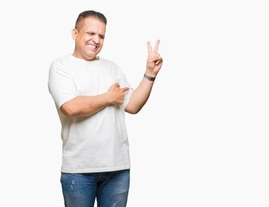 Orta yaş Arap adam wearig t-shirt mutlu yüz zafer işareti yaparken kameraya göz kırpıyor ile gülümseyen izole arka plan üzerinde beyaz. İki numaralı.