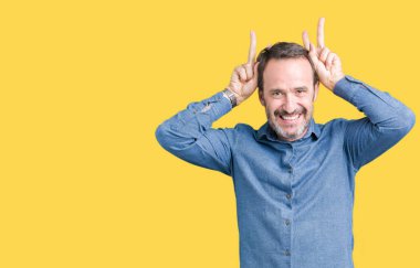 Neşeli gülümseyen yakışıklı orta yaş zarif üst düzey adam komik ve çılgın baş parmaklar ile kulakları, tavşan poz izole arka plan