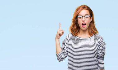 İzole arka plan başarılı fikirle parmağı yukarıyı gözlüklü genç güzel kadın. Çıktıktan ve mutlu. Bir numara.