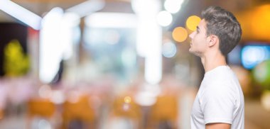 Tarafına, seyir izole arka plan üzerinde beyaz t-shirt giyen genç yakışıklı adam sakin ol kendine güvenen gülümseme ile doğal yüz pozuyla profili.