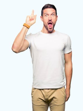Casual beyaz t-shirt işaret parmağı ile başarılı fikir giyen yakışıklı adam. Çıktıktan ve mutlu. Bir numara.