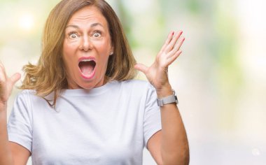 Orta yaş üst düzey İspanyol kadın deli kutluyor arka plan izole ve başarı için kaldırdı kollarını açarak hayrete ve heyecanlı çığlık gözleri açık. Kazanan kavramı