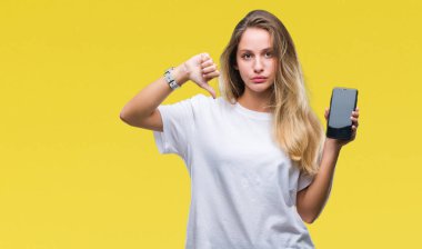 Genç güzel sarışın kadın gösteren ekran smartphone kızgın yüzü, eksi işareti aşağı antipati başparmak ile gösterilen, ret kavramı ile izole arka plan üzerinde