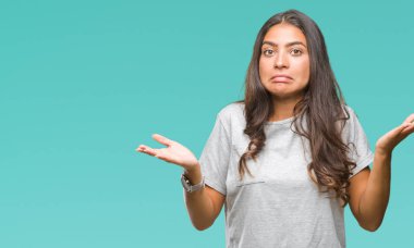 Genç güzel Arap kadın izole arka plan clueless ve şaşkın bir ifadeyle kollar ve eller kaldırdı. Şüphe kavramı.