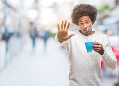 Dur işareti ile ciddi ve kendine güvenen ifade, savunma hareketi yaparken açık el ile izole arka plan üzerinde kahve içme Afro Amerikalı adam