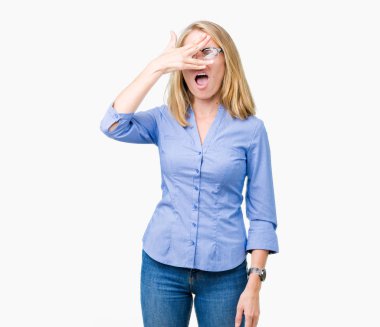 Mahcup ifadeyle parmaklarımın arasından seyir yüz ve gözler el ile kapsayan şok izole arka plan bakmak üzerinde güzel genç iş kadını.