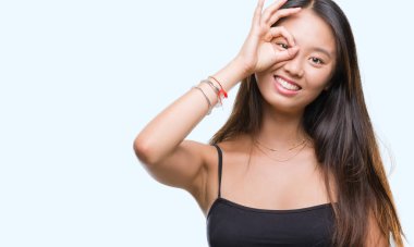 Genç Asyalı kadın gülümsüyor, parmakları ile mutlu yüz üzerinden seyir göz el ile ok jest yapıyor izole arka plan üzerinde.