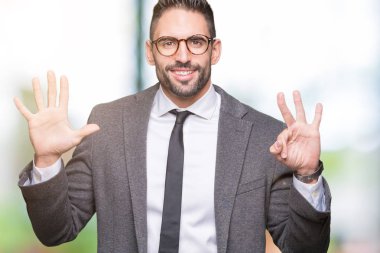 Genç yakışıklı iş adamı gösterilen ve parmakları ile işaret izole arka plan üzerinde kendinden emin ve mutlu gülümseyerek süre sekiz numara.