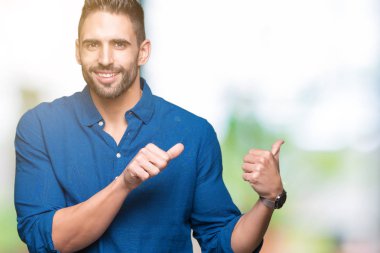 Yakışıklı delikanlı izole arka plan üzerinde emin gülümseyen arkasından el ve kadar başparmak ile işaret