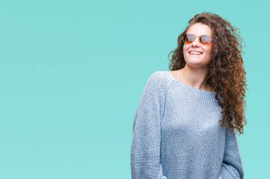 Güzel esmer kıvırcık saçlı Genç kız üzerinde güneş gözlüğü takıyor arka plan uzak tarafına gülümseme ile yüzünde, doğal ifade arıyorum izole. Kendine güvenen gülüyor.