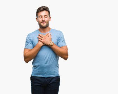 Yakışıklı delikanlı ile gülümseyen izole arka plan üzerinde kapalı gözler ve yüzünde minnettar jest ile göğüs üzerinde eller. Sağlık kavramı.