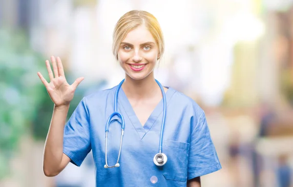 年轻美丽的金发医生外科医生护士妇女在孤立的背景显示和指向与手指数字五同时微笑自信和快乐 — 图库照片