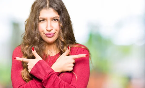 赤いセーターを着ている若い美しい女性別の方向の反対の指で両側を指して — ストック写真