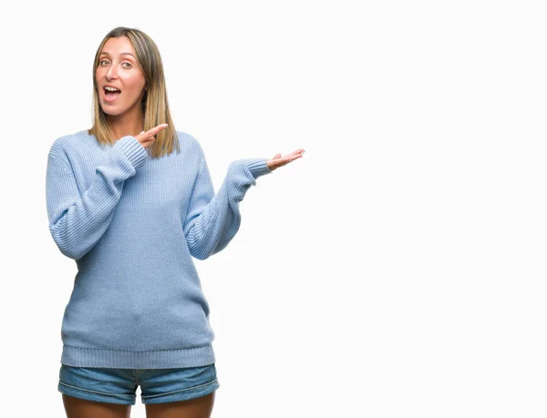 驚くし 手とを提示 指で指している間カメラに笑顔孤立の背景に冬のセーターを着ている若い美しい女性 — ストック写真