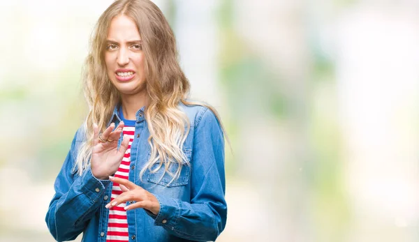 Beautiful young blonde woman over isolated background disgusted expression, displeased and fearful doing disgust face because aversion reaction. With hands raised. Annoying concept.