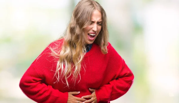 Beautiful young blonde woman wearing winter sweater over isolated background with hand on stomach because indigestion, painful illness feeling unwell. Ache concept.