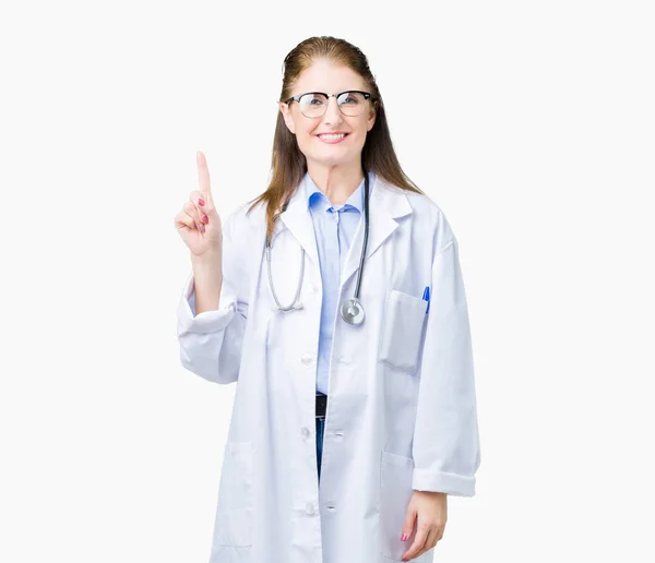 中年成熟的医生妇女穿着医疗外套在孤立的背景显示和手指第一 同时微笑着自信和快乐 — 图库照片