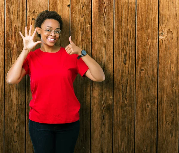 Beautiful young african american woman wearing glasses over isolated background showing and pointing up with fingers number six while smiling confident and happy.