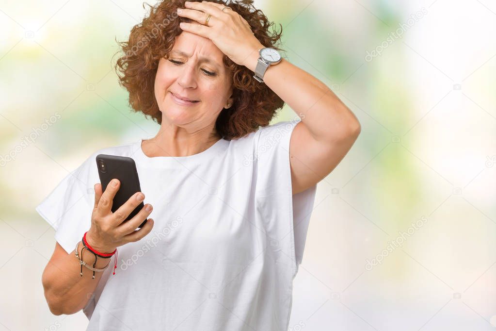 Middle ager senior woman using and texting with smartphone over isolated background stressed with hand on head, shocked with shame and surprise face, angry and frustrated. Fear and upset for mistake.