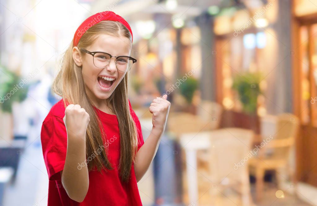 Young beautiful girl wearing glasses over isolated background very happy and excited doing winner gesture with arms raised, smiling and screaming for success. Celebration concept.