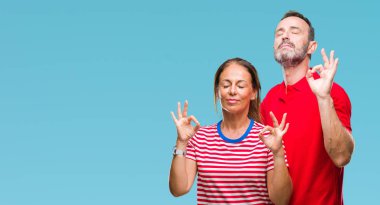 Orta yaş İspanyol çift izole arka plan üzerinde aşık rahatla ve gülümseyen gözlerle kapalı parmak jestle meditasyon yapıyor. Yoga kavramı.