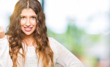 Kendine güvenen ifade el ve parmak ile İtalyan jest yapıyor beyaz kazak giyen genç güzel kadın