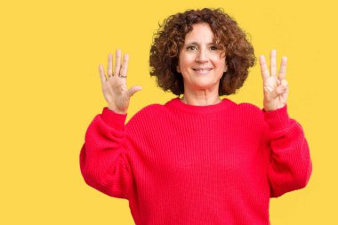 Güzel orta ager kadın kıdemli kırmızı kış kazak üzerinde gösterilen arka plan izole ve parmakları ile işaret gülümseyen ise kendinden emin ve mutlu 8 numaralı.