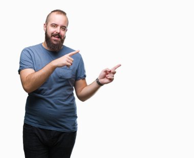 Genç beyaz hipster adam gülümseyerek ve iki elleri ve parmakları ile tarafına işaret kamera bakarak izole arka plan.