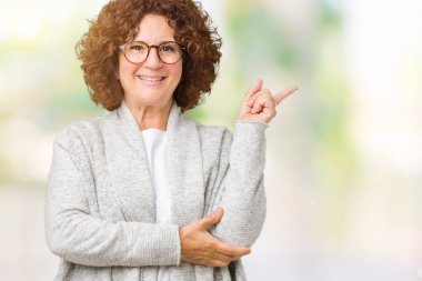 Kameraya bakarak yan el ve parmak ile işaret ceket ve gözlük yüzünde kocaman bir gülümseme ile izole arka plan üzerinde giyen güzel orta ager üst düzey kadın.