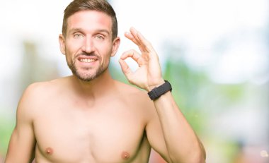 El ve parmak ile ok işareti yapıyor olumlu gösterilen çıplak göğüs gülümseyen yakışıklı gömleksiz adam. Başarılı ifade.