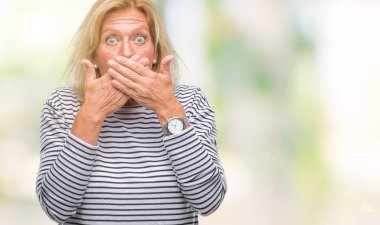 Orta yaş sarışın kadın izole arka plan ağız hata için elleriyle kapsayan şok yüzünden. Gizli kavramı.