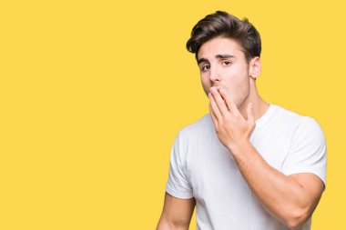 Yakışıklı delikanlı izole arka plan üzerinde beyaz t-shirt giyen el ağzıyla kapsayan yorgun esneme sıkılmış. Restless ve uyku hali.