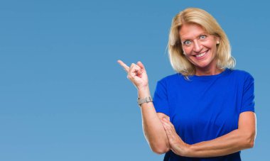 Kameraya bakarak yan el ve parmak ile işaret orta yaş sarışın kadın yüzünde kocaman bir gülümseme ile izole arka plan.