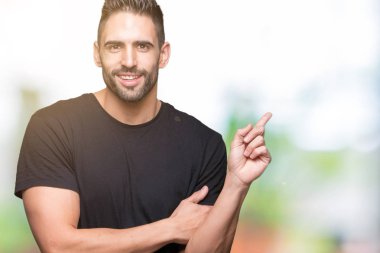 Kameraya bakarak yan el ve parmak ile işaret eden genç yakışıklı adam yüzünde kocaman bir gülümseme ile izole arka plan üzerinde.