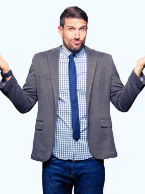 Yakışıklı iş adamı giyen takım elbise ve clueless ve şaşkın bir ifadeyle kollar ve eller kaldırdı kravat. Şüphe kavramı.