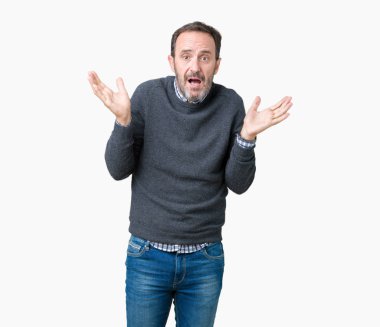 Yakışıklı orta yaş komuta sizde izole arka plan clueless ve şaşkın bir ifadeyle kollar ve eller kaldırdı üzerinde bir kazak giyiyor. Şüphe kavramı.