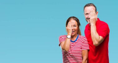 Orta yaş İspanyol çift el yüz ve sürpriz duygu kendinden emin gülümseme ile tek gözüyle kapsayan izole arka plan üzerinde aşık.