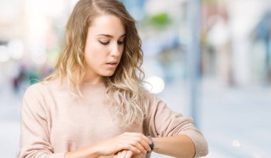 Sweatershirt kol saati, rahat ve kendinden emin zamanında kontrol izole arka plan üzerinde giyen genç güzel sarışın kadın