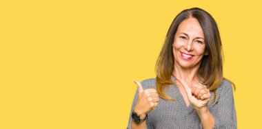 Güzel orta yaş iş kadını emin gülümseyen arkasından el ve kadar başparmak ile işaret