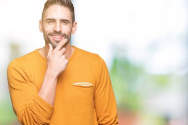 Yakışıklı delikanlı emin çapraz kollar ve çeneme kaldırdı el ile gülümseme ile kameraya bakarak izole arka plan üzerinde. Pozitif düşünce.