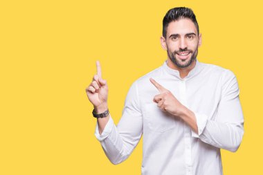 Gülümseyen ve iki elleri ve parmakları ile tarafına işaret kamera bakarak arka plan üzerinde genç iş adamı izole.