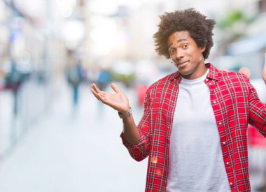 İzole arka plan clueless ve şaşkın bir ifadeyle kollar ve eller kaldırdı Afro Amerikan adam. Şüphe kavramı.