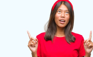 Genç Asyalı kadın izole arka plan üzerinden hayran ve yukarıya bakıp parmakları ile işaret şaşırttı ve silah kaldırdı.