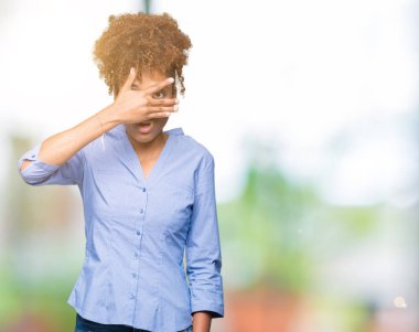 Mahcup ifadeyle parmaklarımın arasından seyir yüz ve gözler el ile kapsayan şok izole arka plan bakmak üzerinde güzel genç Afro-Amerikan iş kadını.