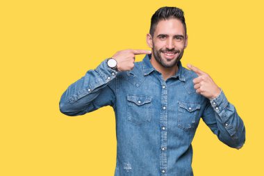 Tecrit edilmiş, güler yüzlü, kendine güvenen, parmaklarını, dişlerini ve ağzını gösteren genç yakışıklı bir adam. Sağlık kavramı.